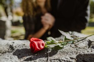 couple mourning with rose on headstone