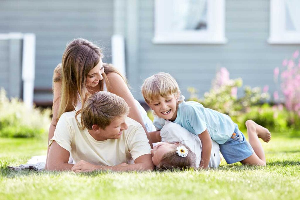 young parents playing on lawn with two children
