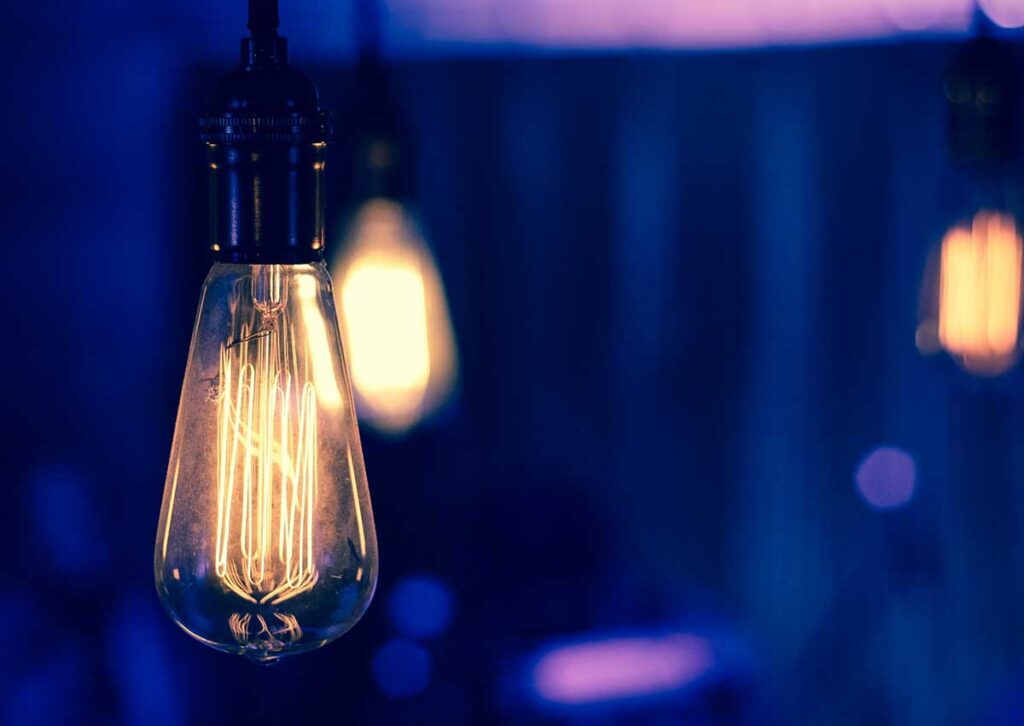a single light bulb glowing on a blurred blue blackground