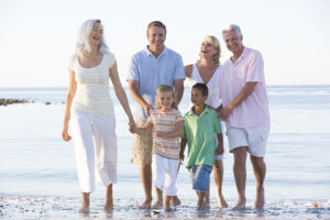 three generations of family smiling on beach