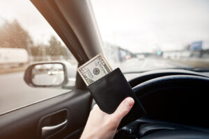 person driving on turnpike holding wallet with money