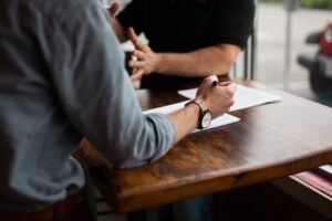 men discussing documents at wooden table