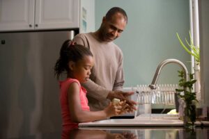 father and daughter washing dishes together