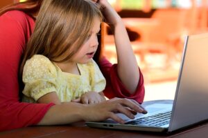 child on mother's lap looking at laptop computer