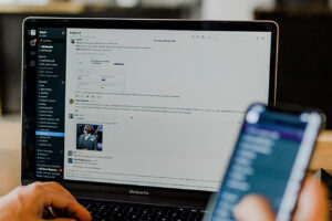 person looking at phone and laptop screens