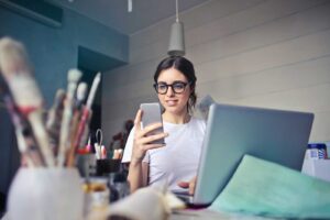 woman working two jobs at one time looking at laptop and phone