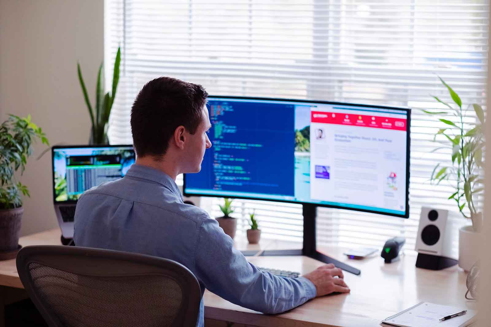 man working two jobs at once looking at multiple computer screens